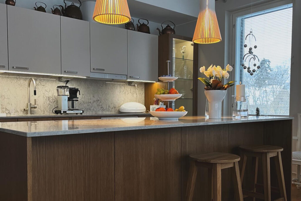 Kuva keittiöstä, jossa pöydällä hedelmiä ja kukkia